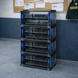 Stack of black storage crates in a room with a desk and bulletin board.